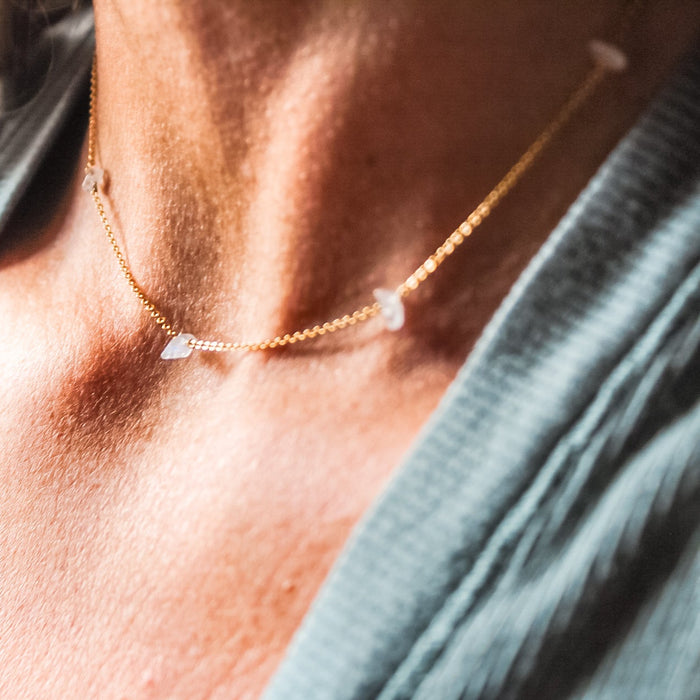 Necklace with small stones worn by a person against a blurred background