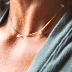 Necklace with small stones worn by a person against a blurred background