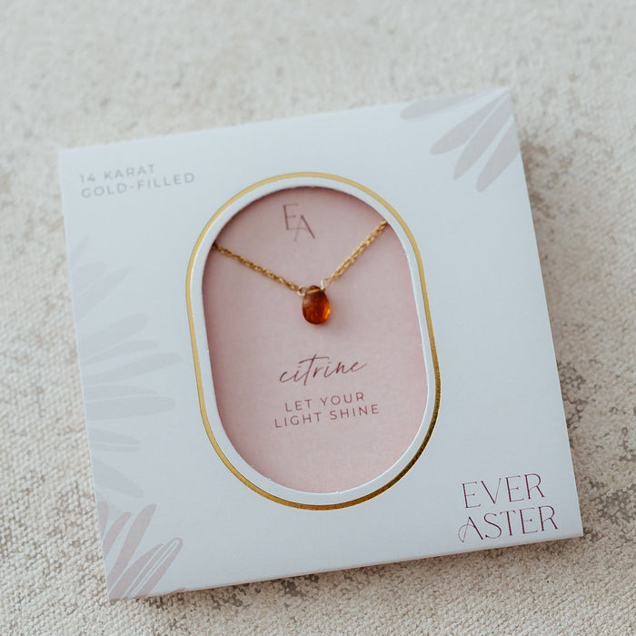 a gold necklace with an amber like gemstone drop that is citrine

