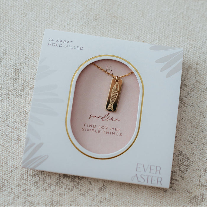 gold bar necklace with a sardine hand stamped onto it hanging on a necklace chain